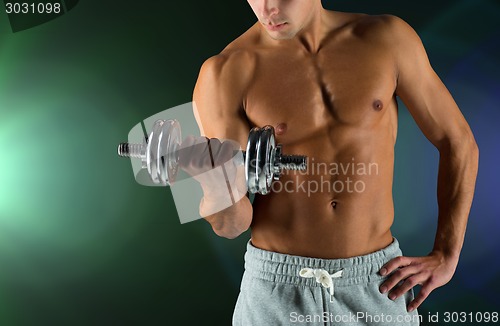 Image of close up of young man with dumbbell flexing biceps