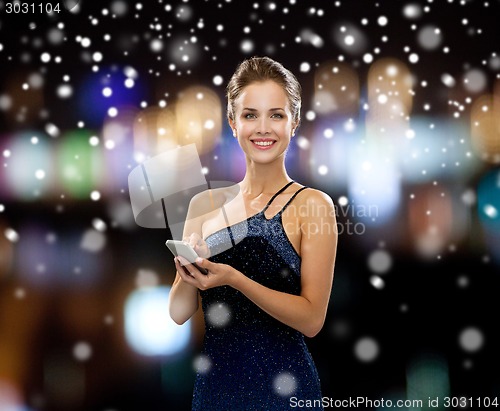 Image of smiling woman in evening dress with smartphone