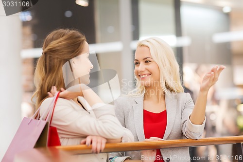 Image of happy young women with shopping bags in mall