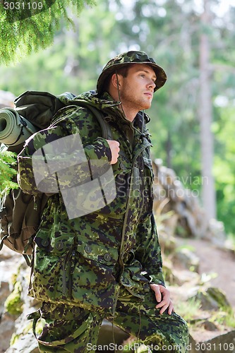 Image of young soldier with backpack in forest