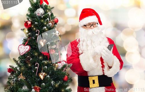 Image of santa claus with smartphone and christmas tree