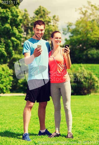 Image of two smiling people with smartphones outdoors