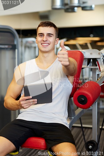 Image of smiling young man with tablet pc computer in gym