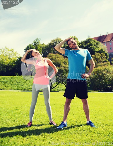 Image of smiling couple stretching outdoors