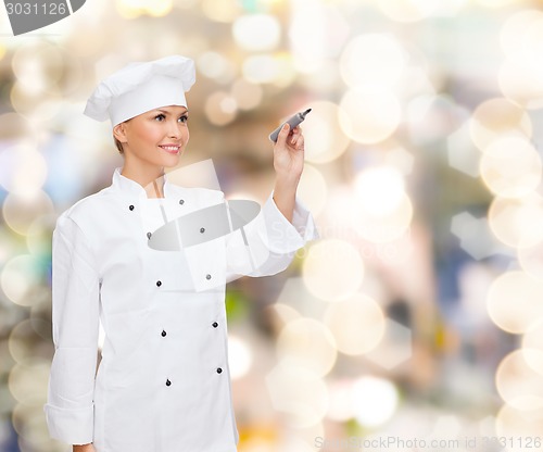 Image of smiling female chef writing something on air