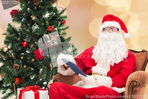 Image of man in costume of santa claus with tablet pc