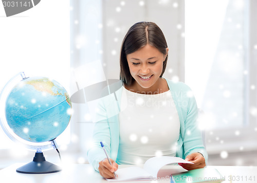 Image of smiling young woman with globe and tablet pc