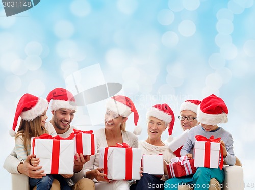 Image of happy family in santa helper hats with gift boxes