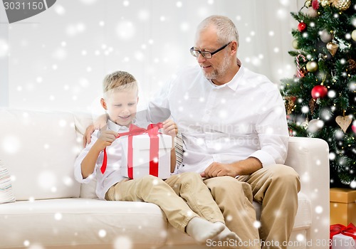 Image of smiling grandfather and grandson with gift box