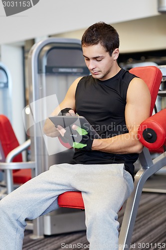 Image of young man with tablet pc computer in gym