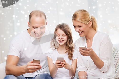 Image of happy family with smartphones at home