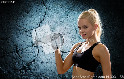 Image of young sporty woman with heavy steel dumbbell