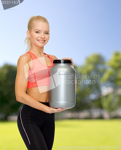 Image of smiling sporty woman with jar of protein