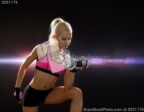 Image of young sporty woman with heavy steel dumbbell