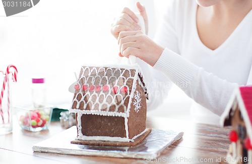 Image of close up of woman making gingerbread house at home