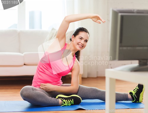 Image of smiling teenage girl streching on floor at home