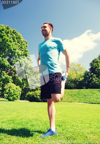 Image of smiling man stretching outdoors