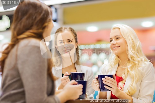 Image of smiling young women with cups in mall or cafe