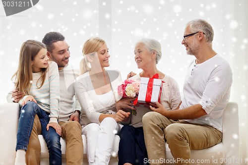 Image of happy family with bunch and gift box at home