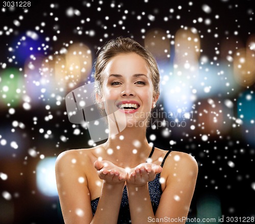 Image of laughing woman in evening dress holding something