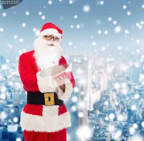 Image of man in costume of santa claus with notepad