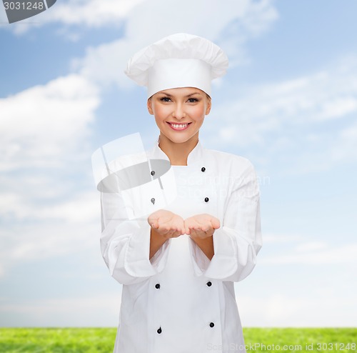 Image of smiling female chef holding something on hands