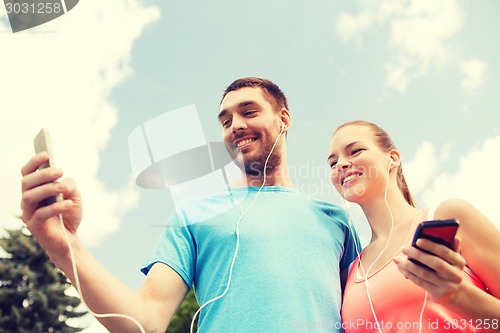 Image of two smiling people with smartphones outdoors