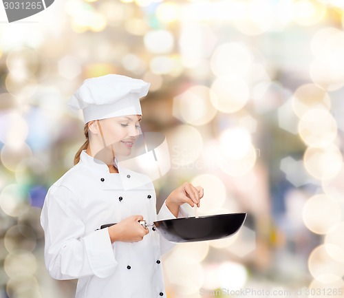 Image of smiling female chef with pan and spoon