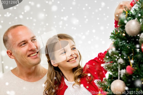 Image of smiling family decorating christmas tree at home