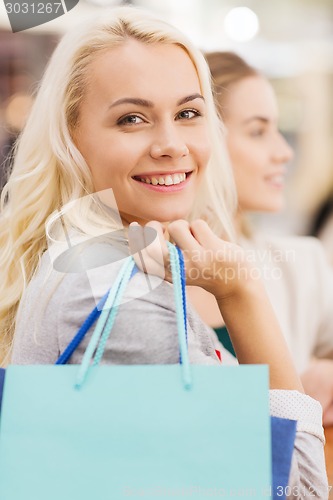 Image of happy young women with shopping bags in mall