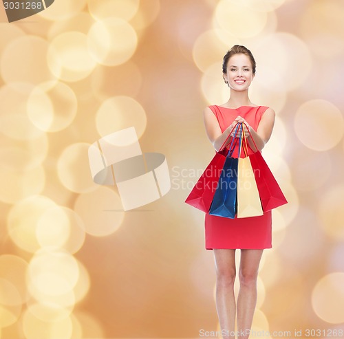 Image of smiling elegant woman in dress with shopping bags