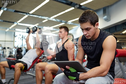 Image of group of men with tablet pc and dumbbells in gym