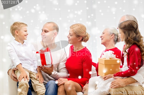 Image of smiling family with gifts talking at home