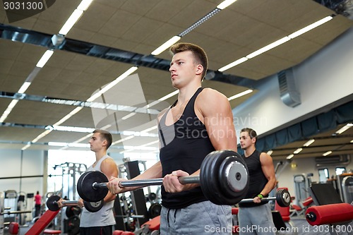 Image of group of men flexing muscles with barbell in gym