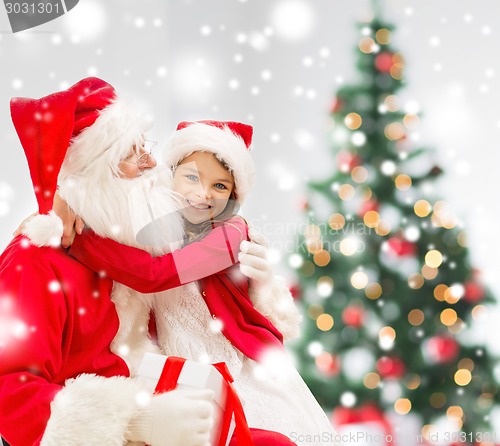 Image of smiling girl with santa claus and gift at home
