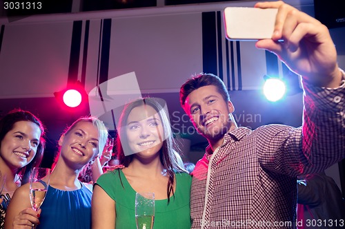 Image of friends with glasses and smartphone in club