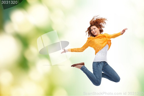 Image of smiling young woman jumping high in air