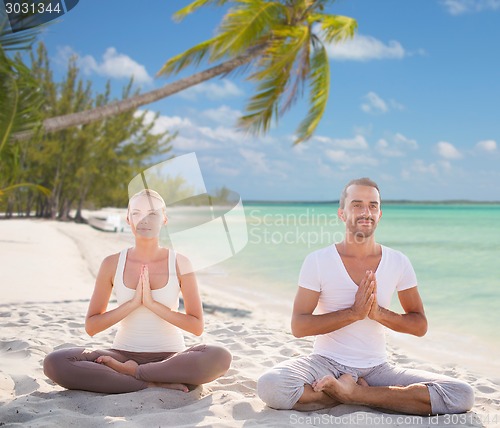 Image of smiling couple meditating on tropical beach