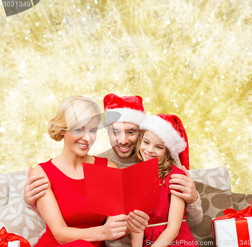 Image of happy family in santa hats with greeting card