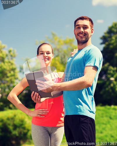 Image of smiling couple with tablet pc outdoors