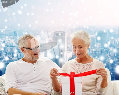 Image of happy senior couple with gift box at home