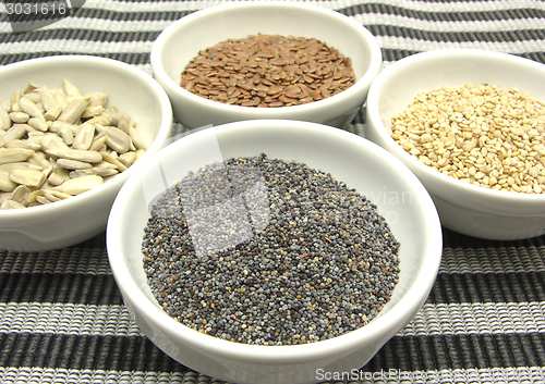 Image of Four bowl with different seeds on a striped background