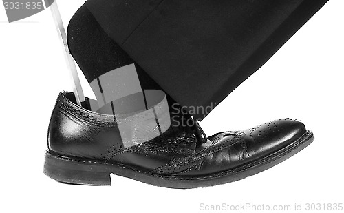 Image of Person wearing black suit and socks entering foot into black lea