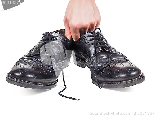 Image of Male hands holding up a pair of worn black leather shoes towards