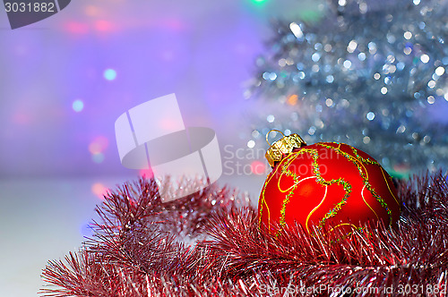 Image of Red Christmas ball under the tree and tinsel