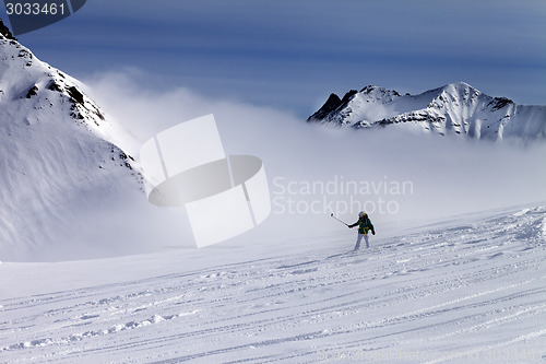 Image of Snowboarder downhill on off-piste slope with newly-fallen snow