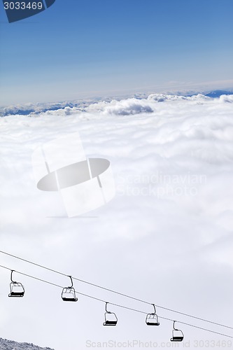 Image of Chair-lift and mountains under clouds in sun day