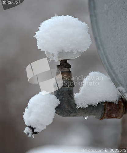 Image of outdoor metal faucet covered by snow