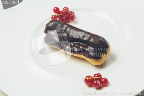 Image of Single chocolate eclair on white  plate