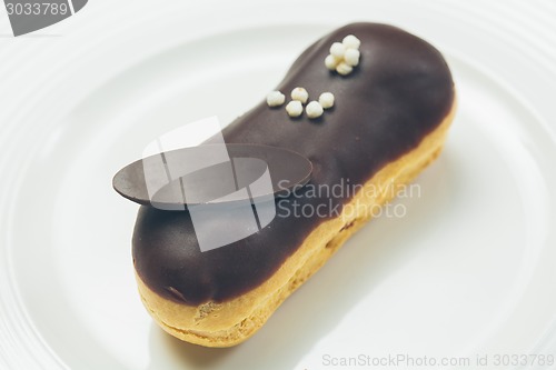 Image of Single chocolate eclair on white  plate